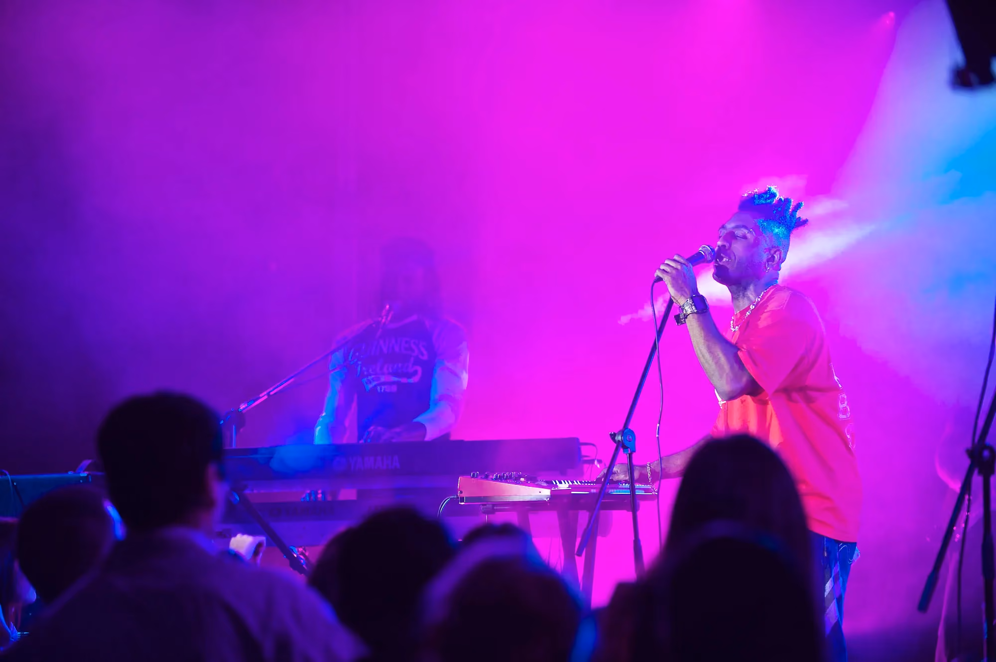 Vocalist performing under magenta and blue stage lighting at a live concert