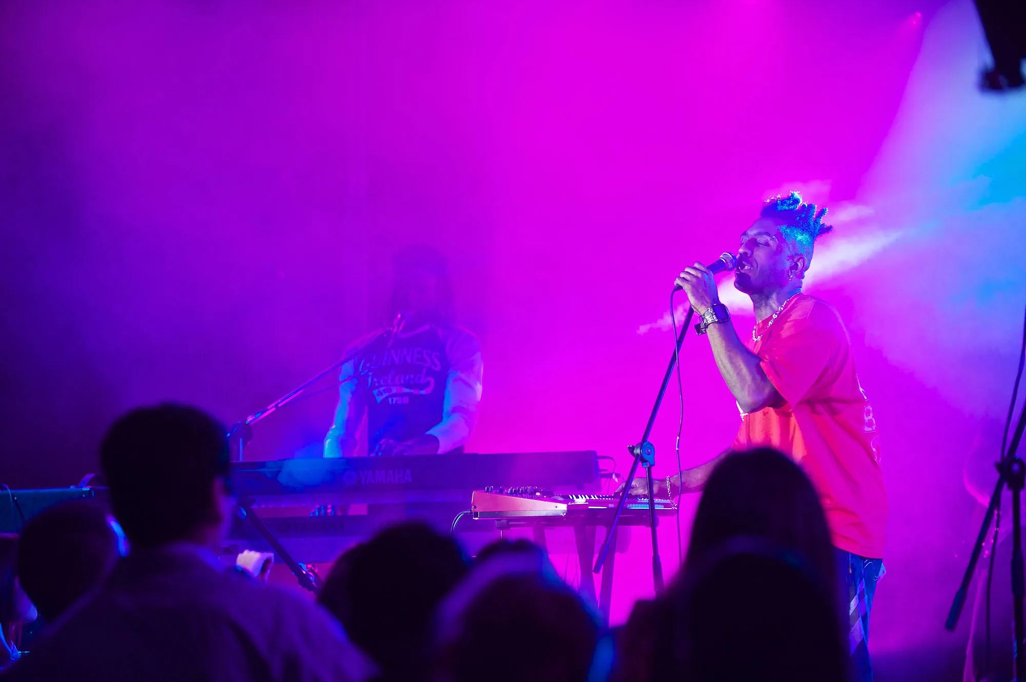 Vocalist performing under magenta and blue stage lighting at a live concert