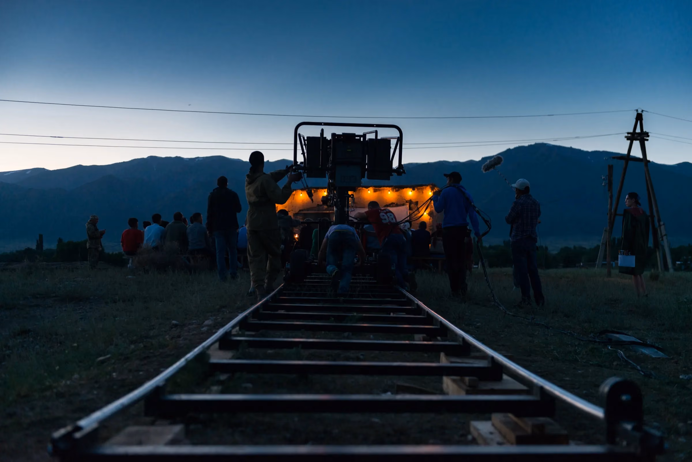 Film crew working around a camera dolly on location at dusk