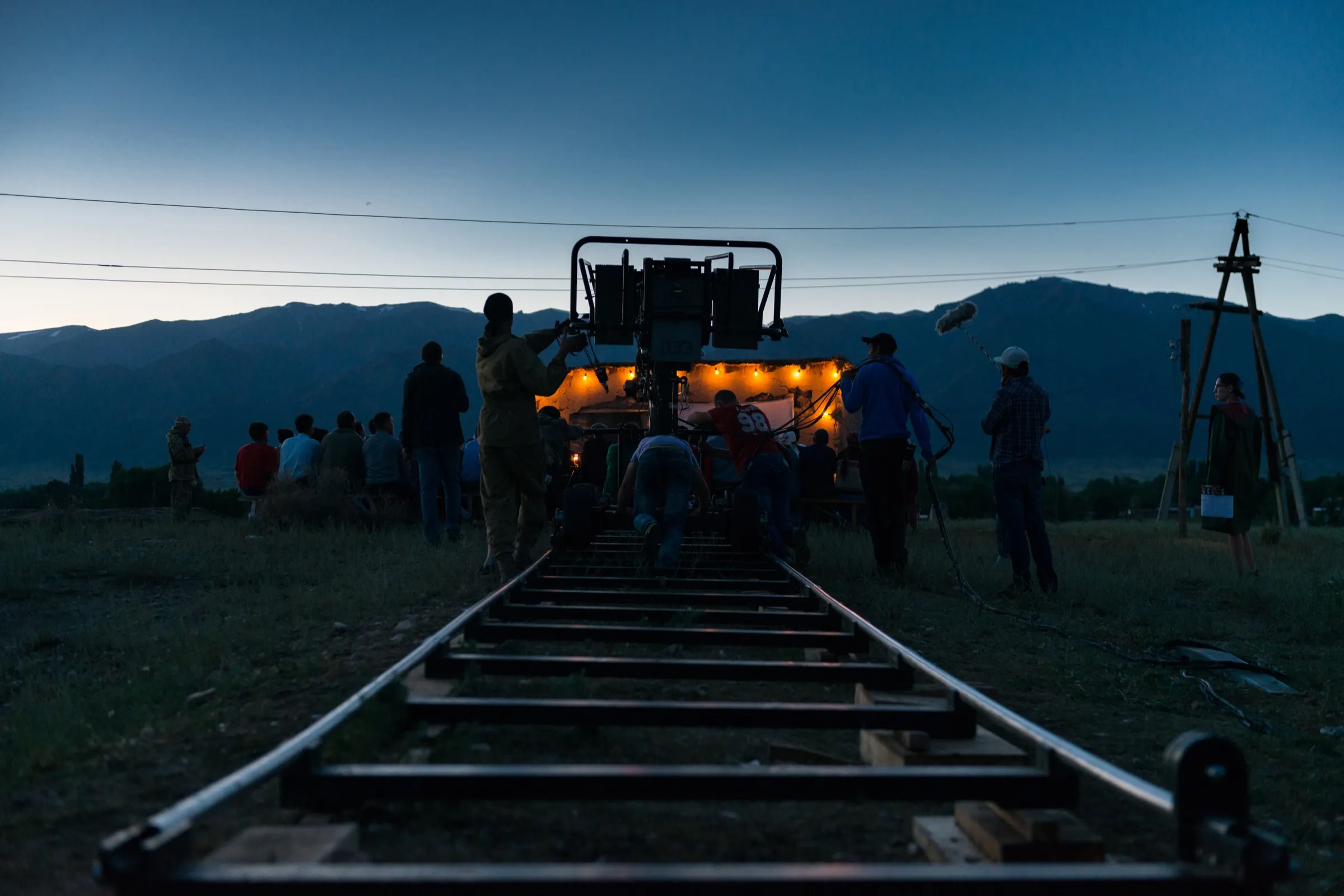 Film crew working around a camera dolly on location at dusk