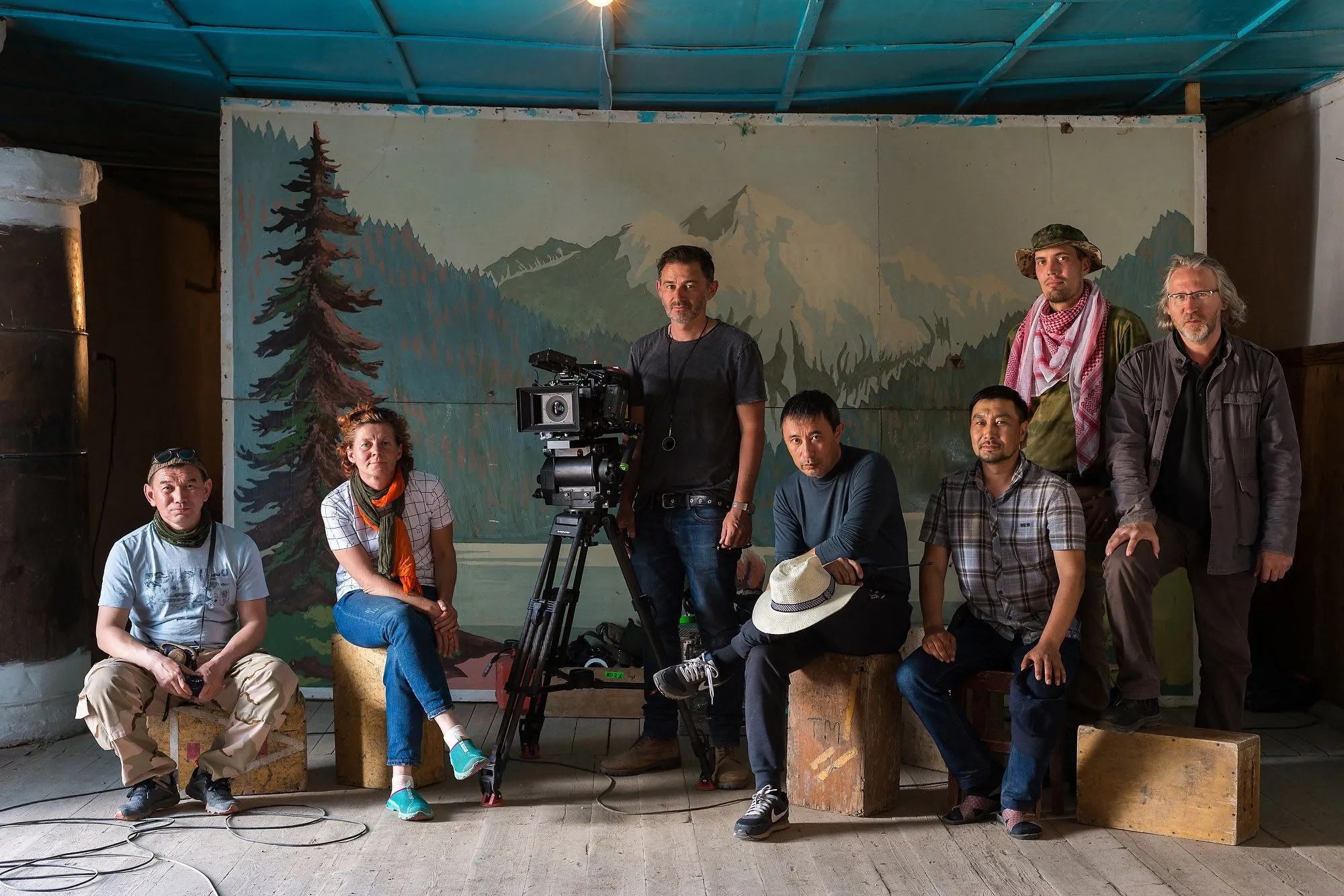 Cast and production crew gathered around a cinema camera on set