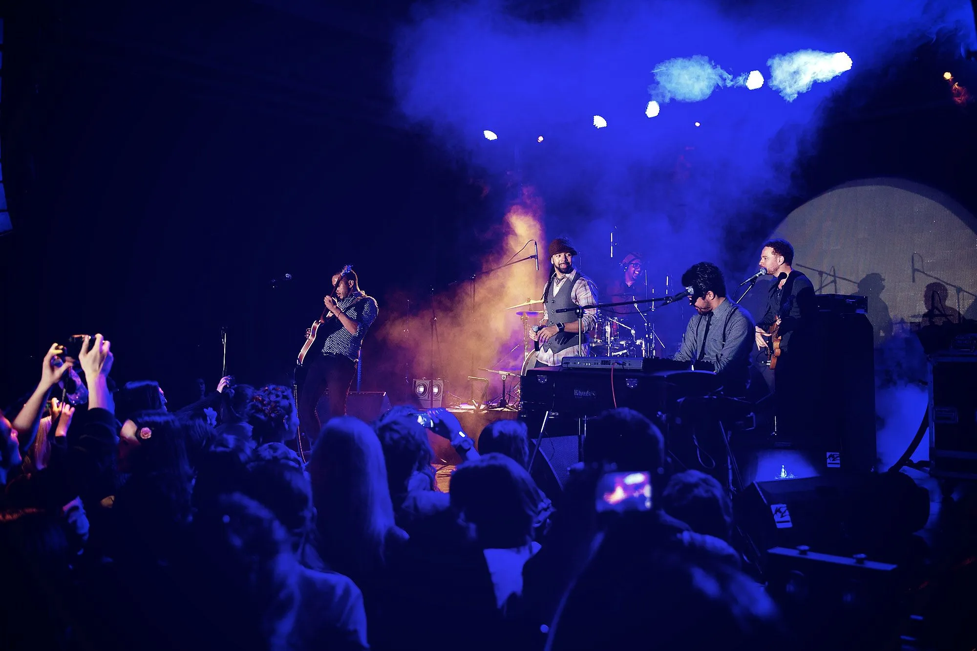 Live band performing through colourful light and atmospheric stage smoke
