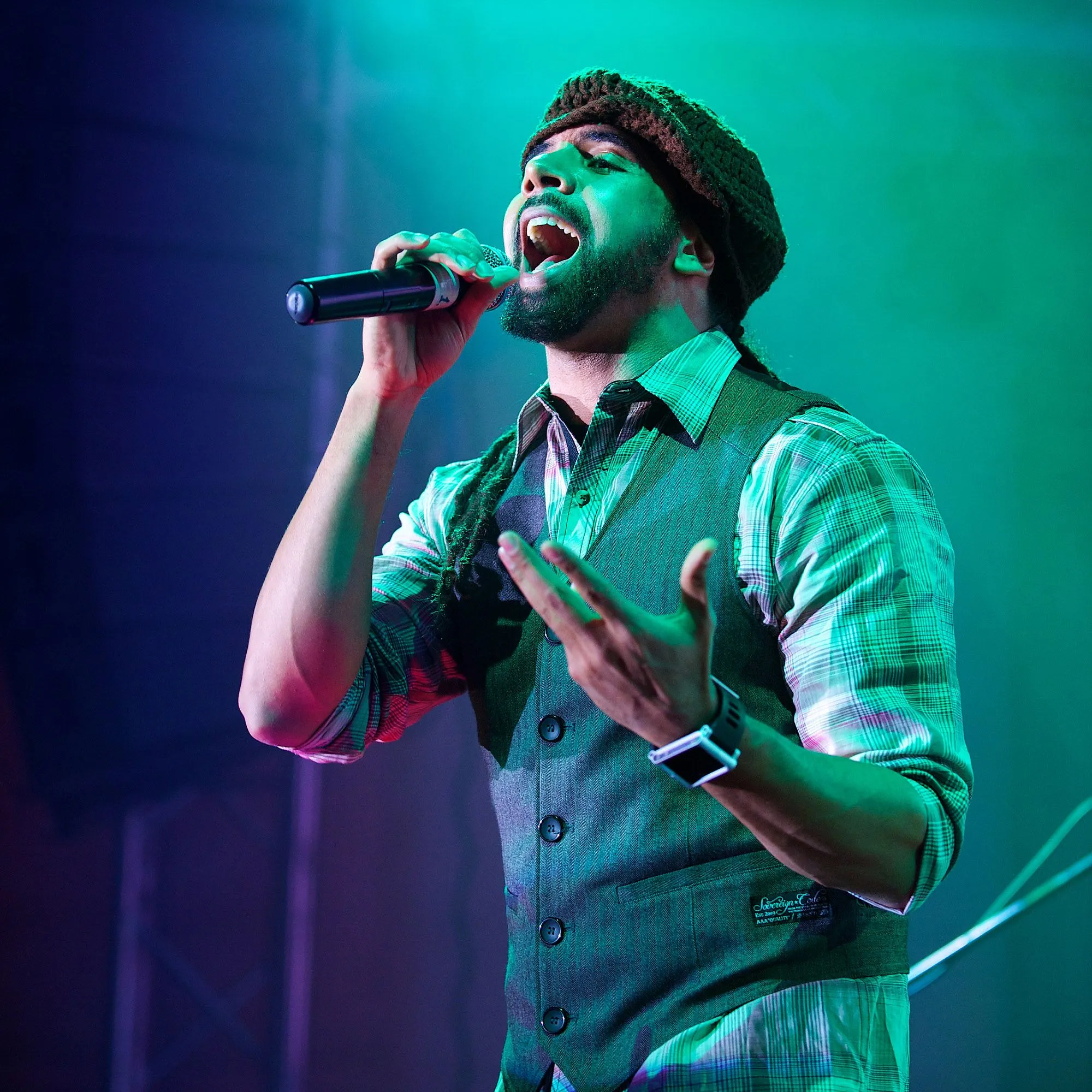 Vocalist performing under green and blue concert lighting