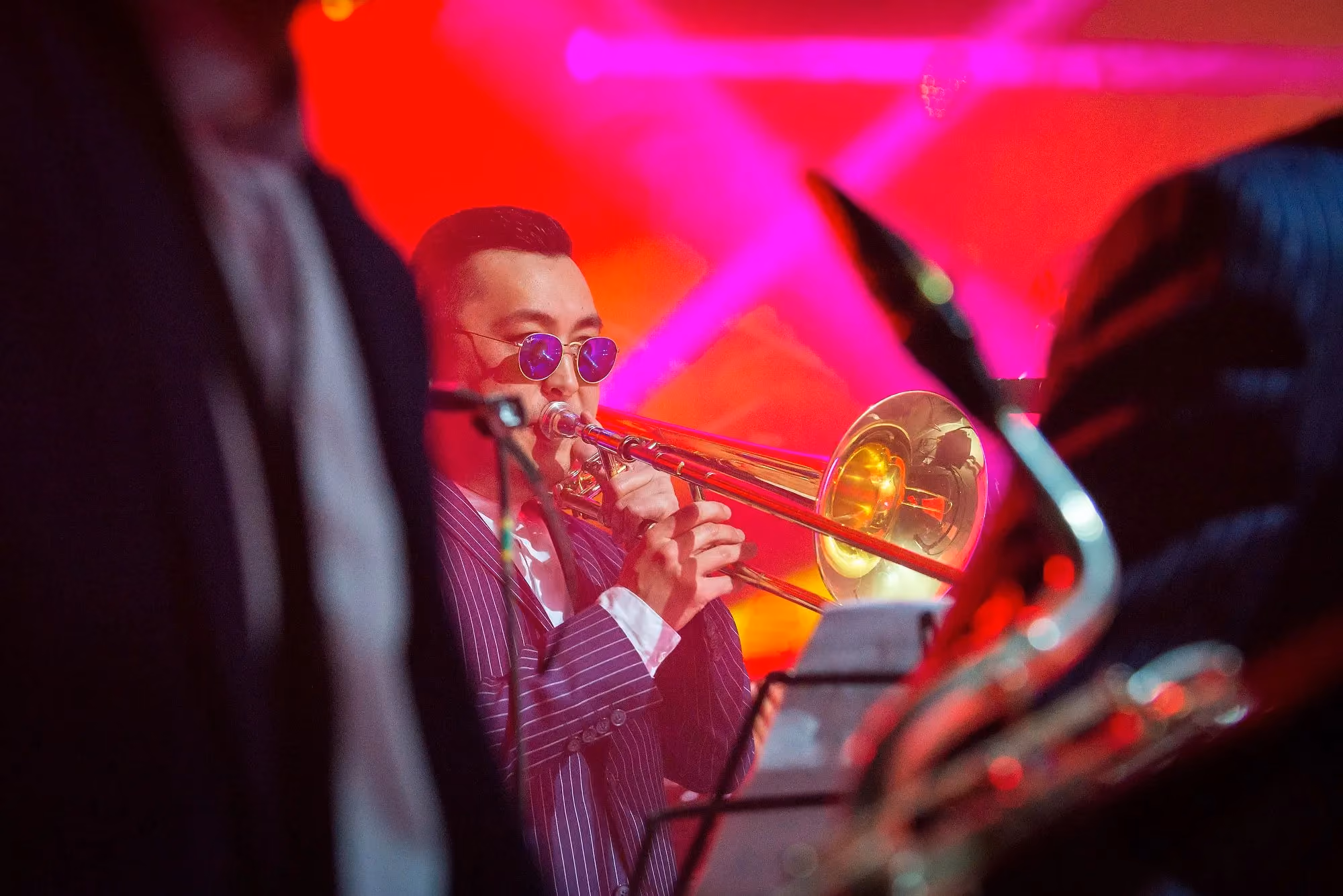 Trombone player performing under vivid red stage lighting