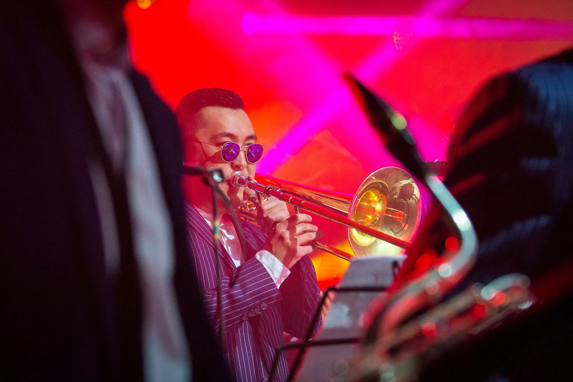 Trombone player performing under vivid red stage lighting