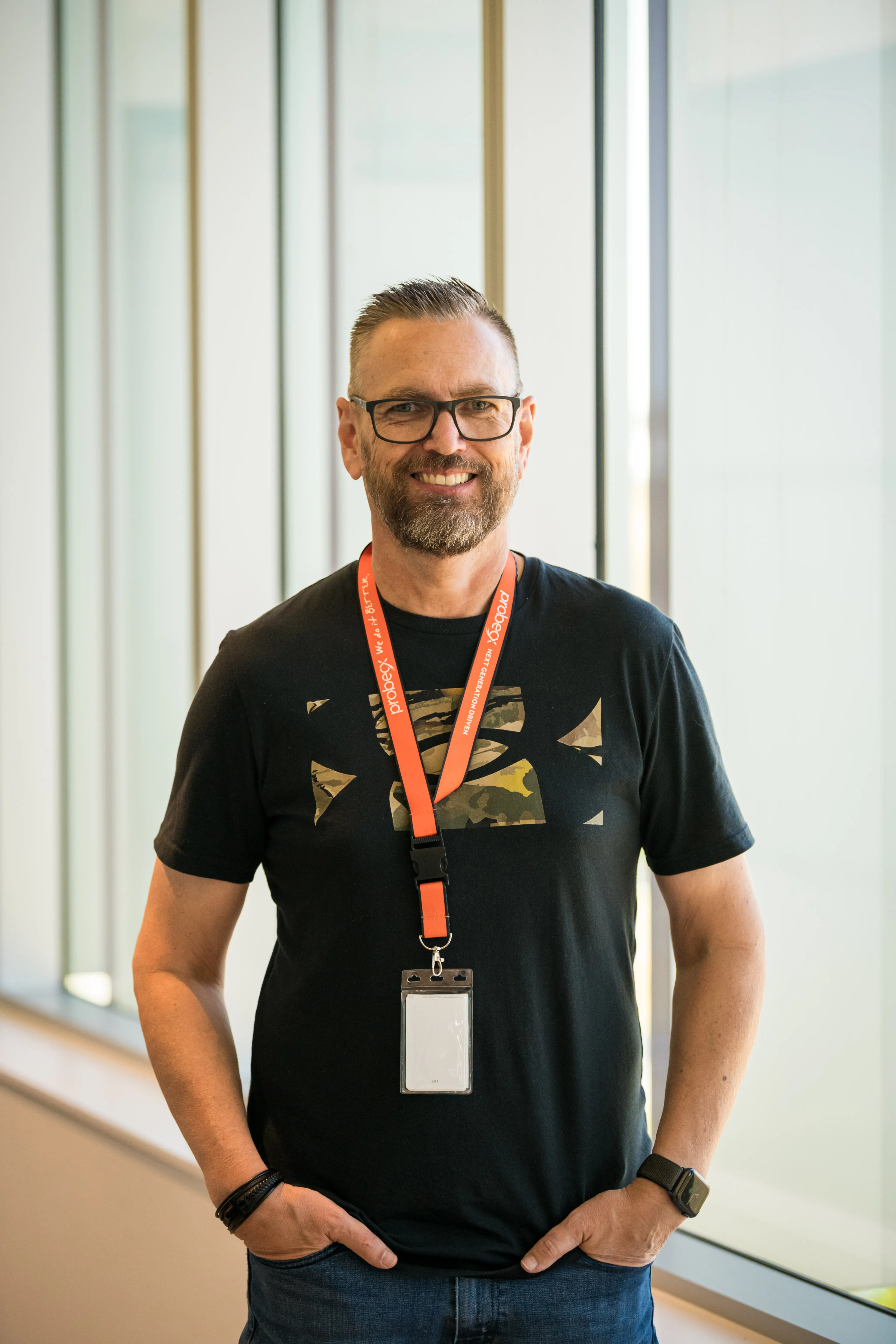 Smiling professional wearing glasses and a black T-shirt in a bright workplace