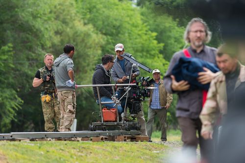 Film crew operating a cinema camera on dolly track outdoors