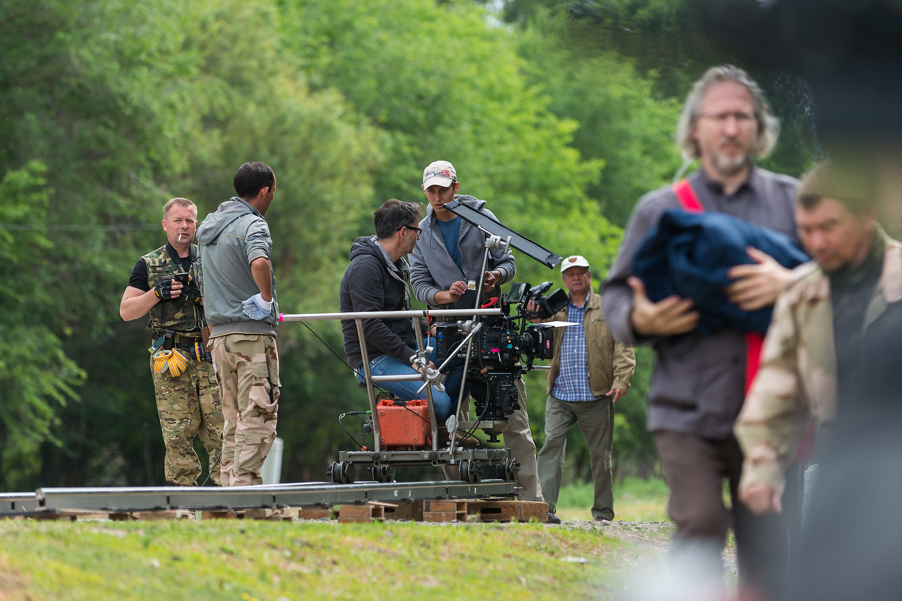 Film crew operating a cinema camera on dolly track outdoors