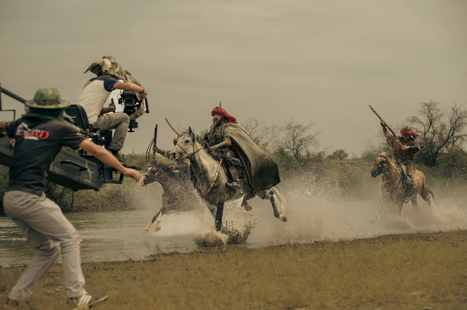Behind-the-scenes view of a camera crew filming horse riders crossing water