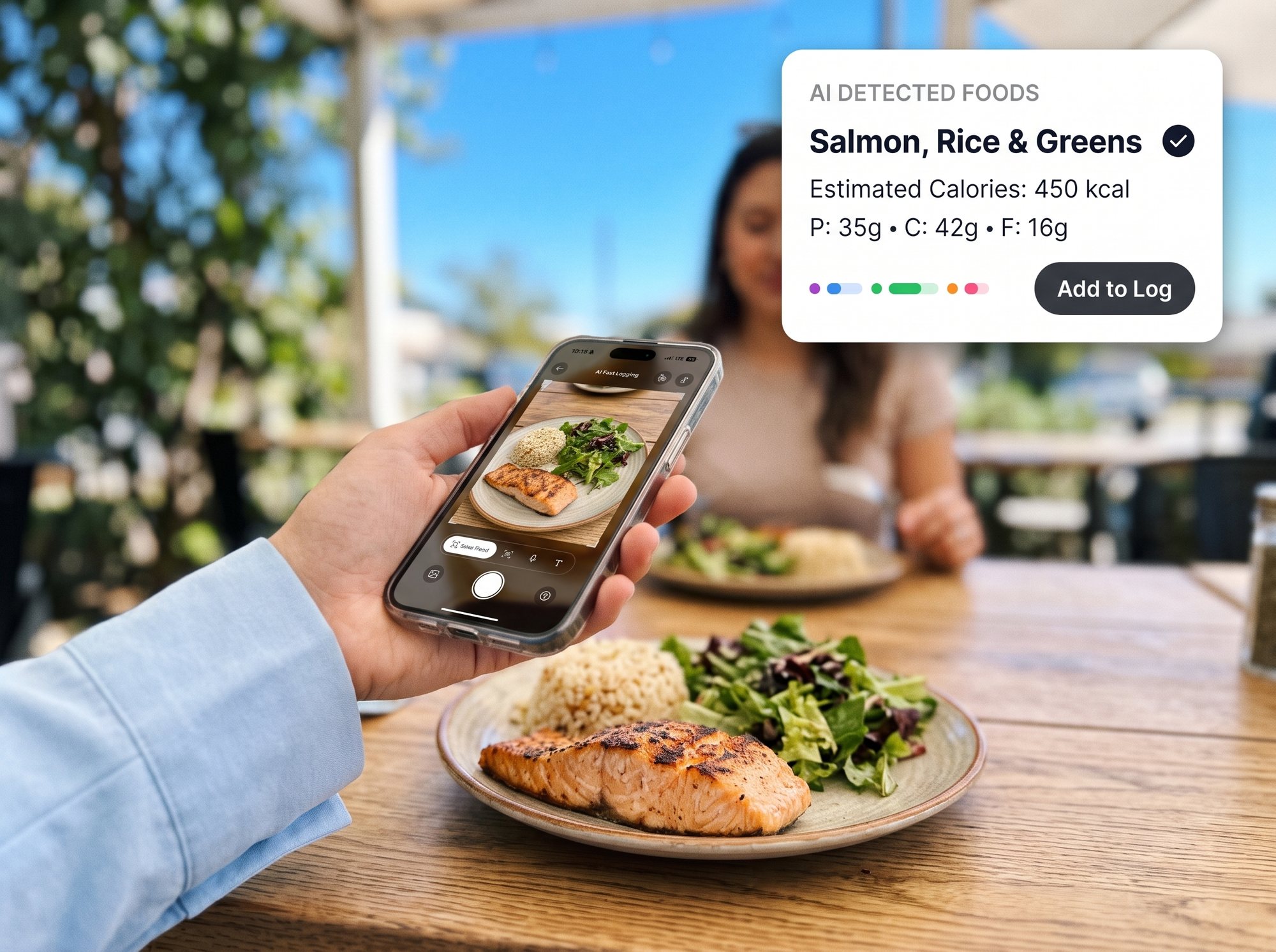 Hand holding a phone over a plated lunch with detected foods and macros shown on screen