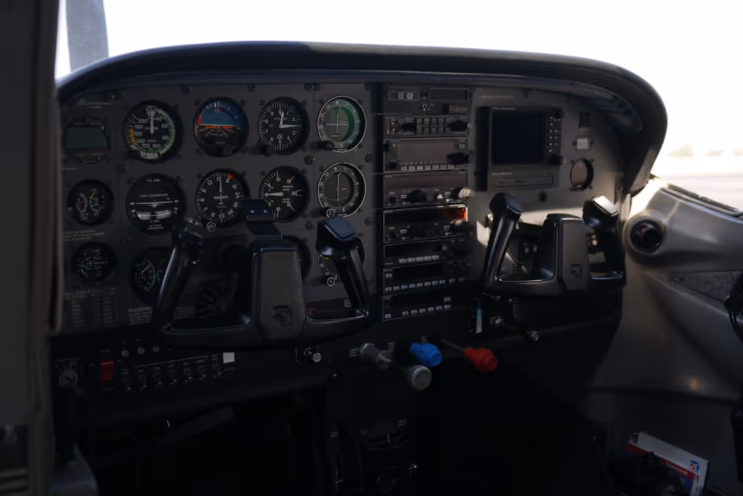 Cockpit of a small aircraft showing flight instruments, control yokes, and radio equipment.