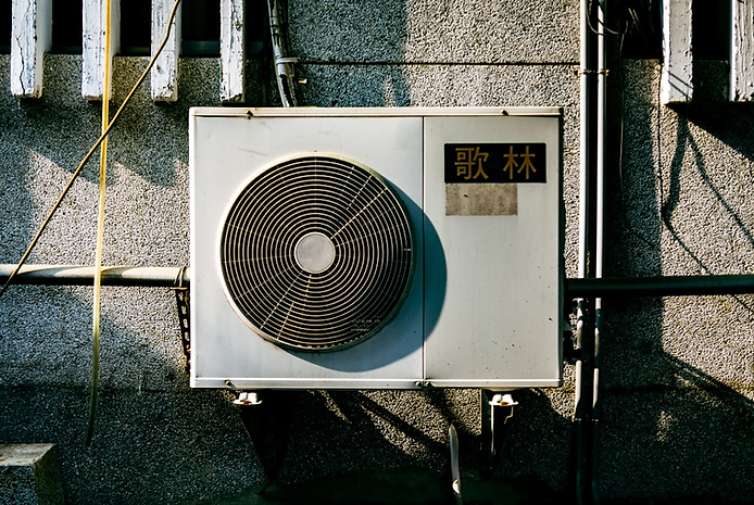 Air conditioning unit mounted on a wall, featuring a circular fan and visible pipes, relevant to heat pump installation and energy efficiency in Eatonville, WA.