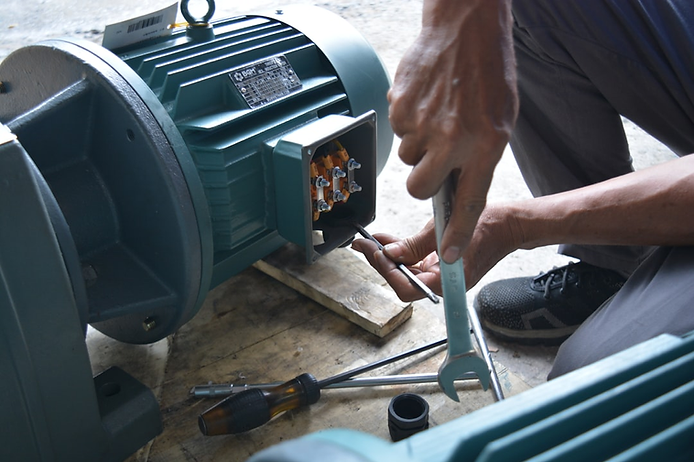 Technician repairing a heat pump motor with tools, emphasizing professional maintenance for HVAC systems in Olympia, WA.