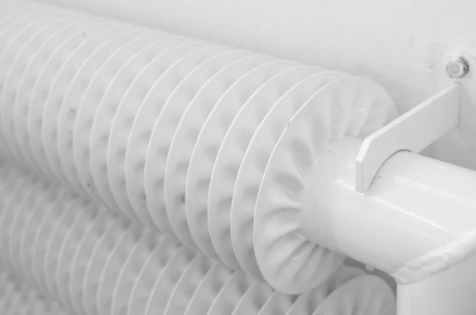 Close-up of a white heating radiator, featuring circular fins, emphasizing heating solutions relevant to home comfort in Olympia, WA.