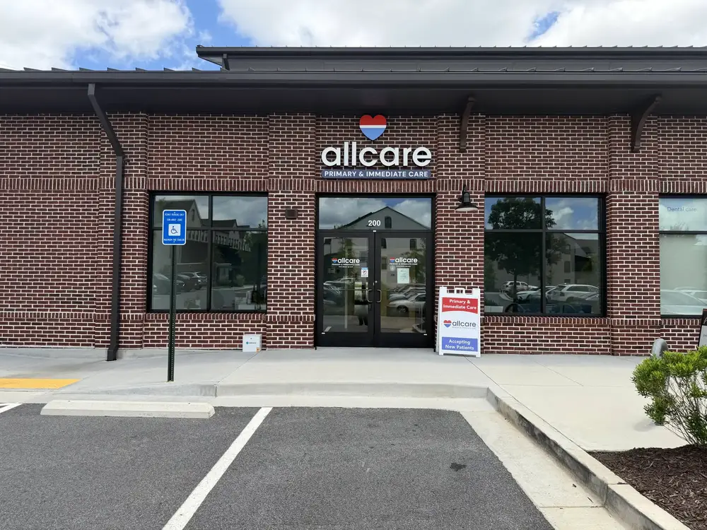 AllCare Halcyon clinic exterior, brick storefront with entrance sign and accessible parking