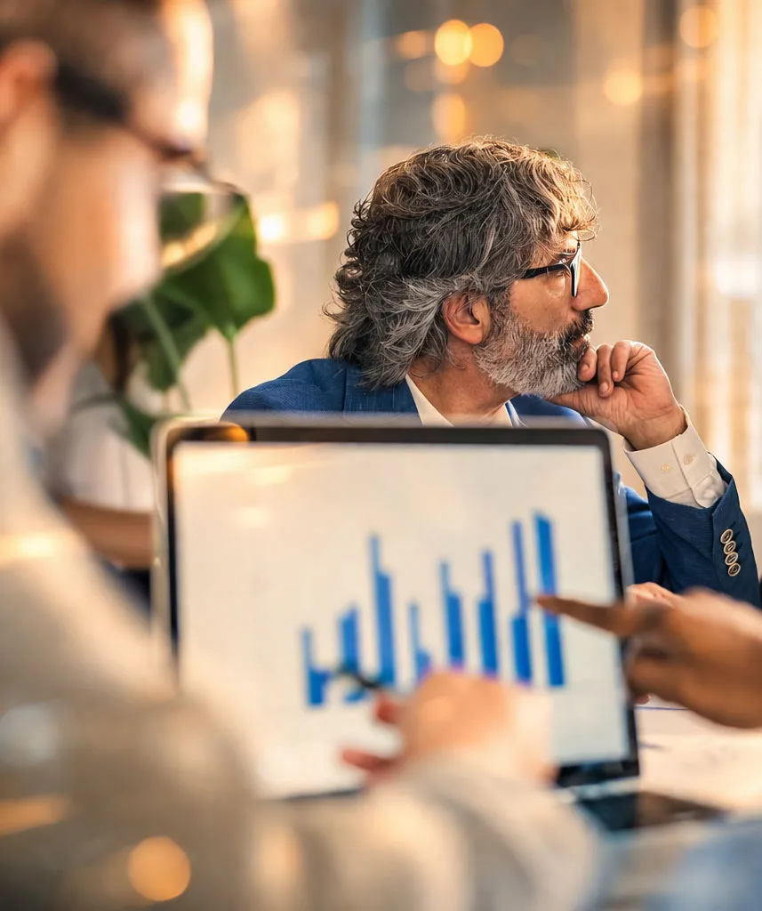 Infusion business professionals analyzing denial analytics on a laptop screen, with the CEO thoughtfully looking to the side.