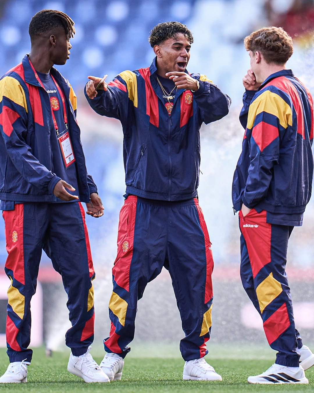 Three young adults wearing soccer jerseys pose confidently in front of a graffiti-covered door.