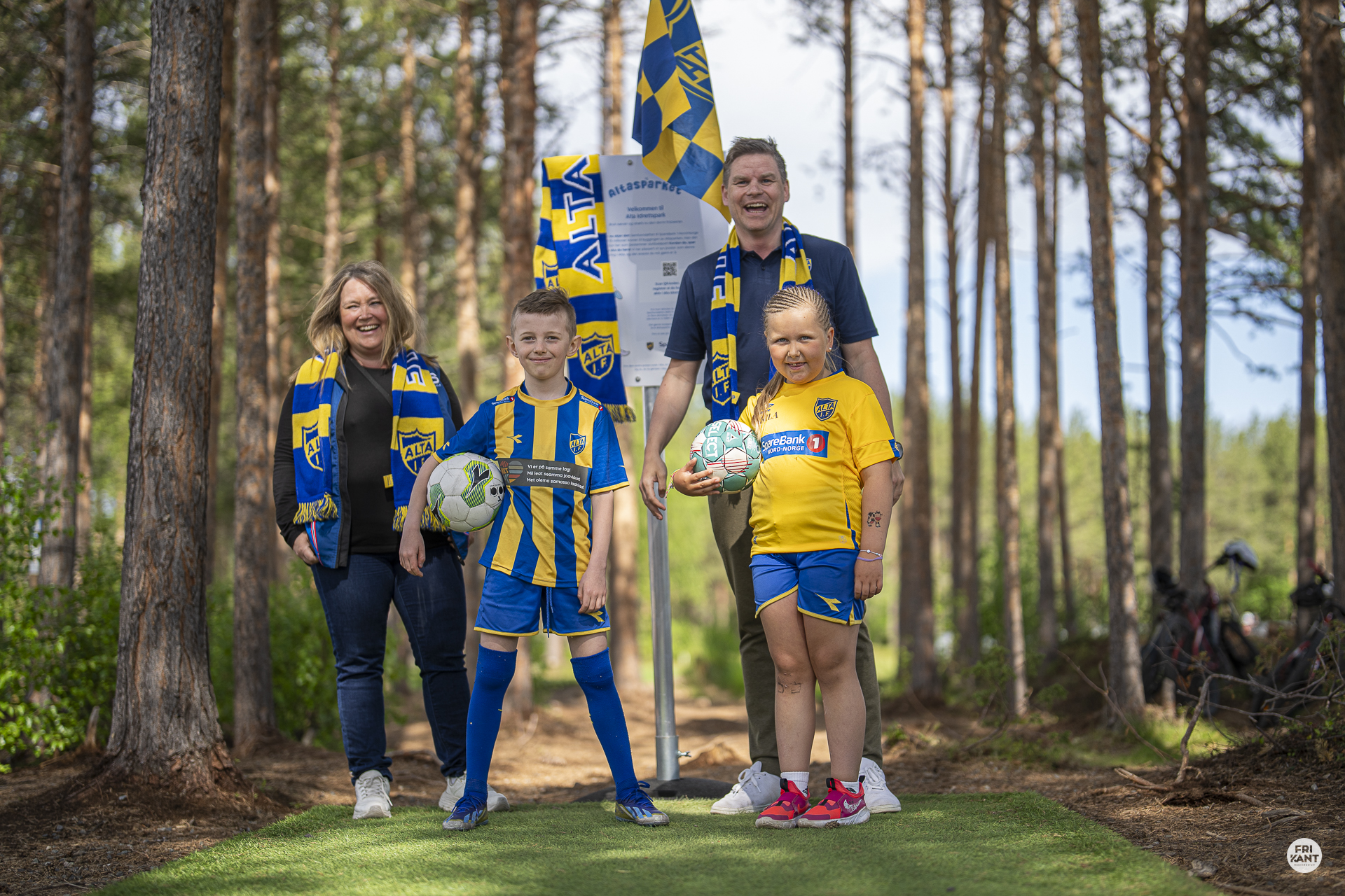 Bilde av Frikant av Altasparket. Avbildet er Sølvi De Jong  fra Sparebank 1 Nord-Norge, Eirik Engelsen og en gutt og en jente ikledd Alta IFs fotballdrakter. Bak dem ser man et skilt fra Altasparket med Alta IF skjerf og flagg.