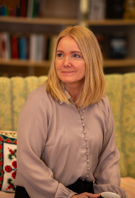Mette Suhr Berg sitter i en sofa og smiler mot venstre. 