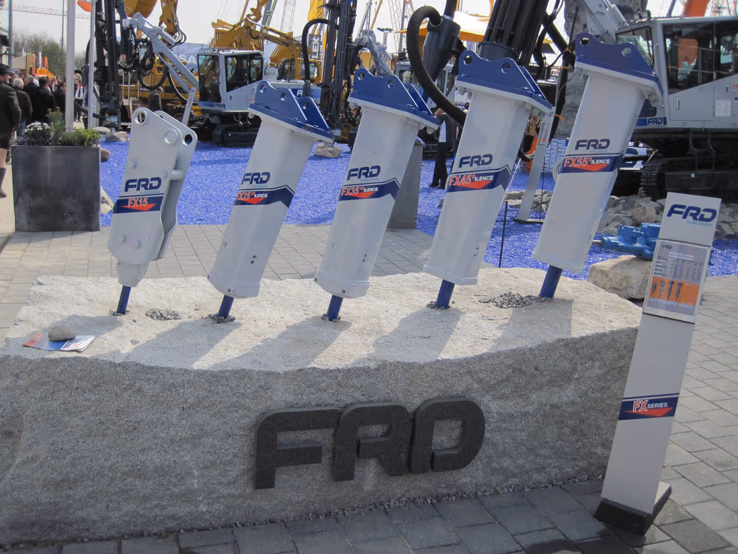Five hydraulic breakers of different sizes displayed on a large stone block with FRD branding.