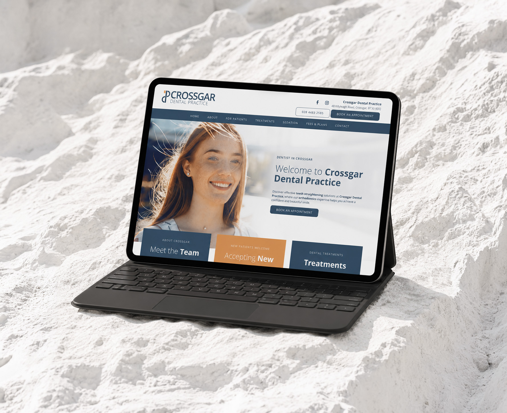 Crossgar Dental Practice website displayed on a laptop on pale stone