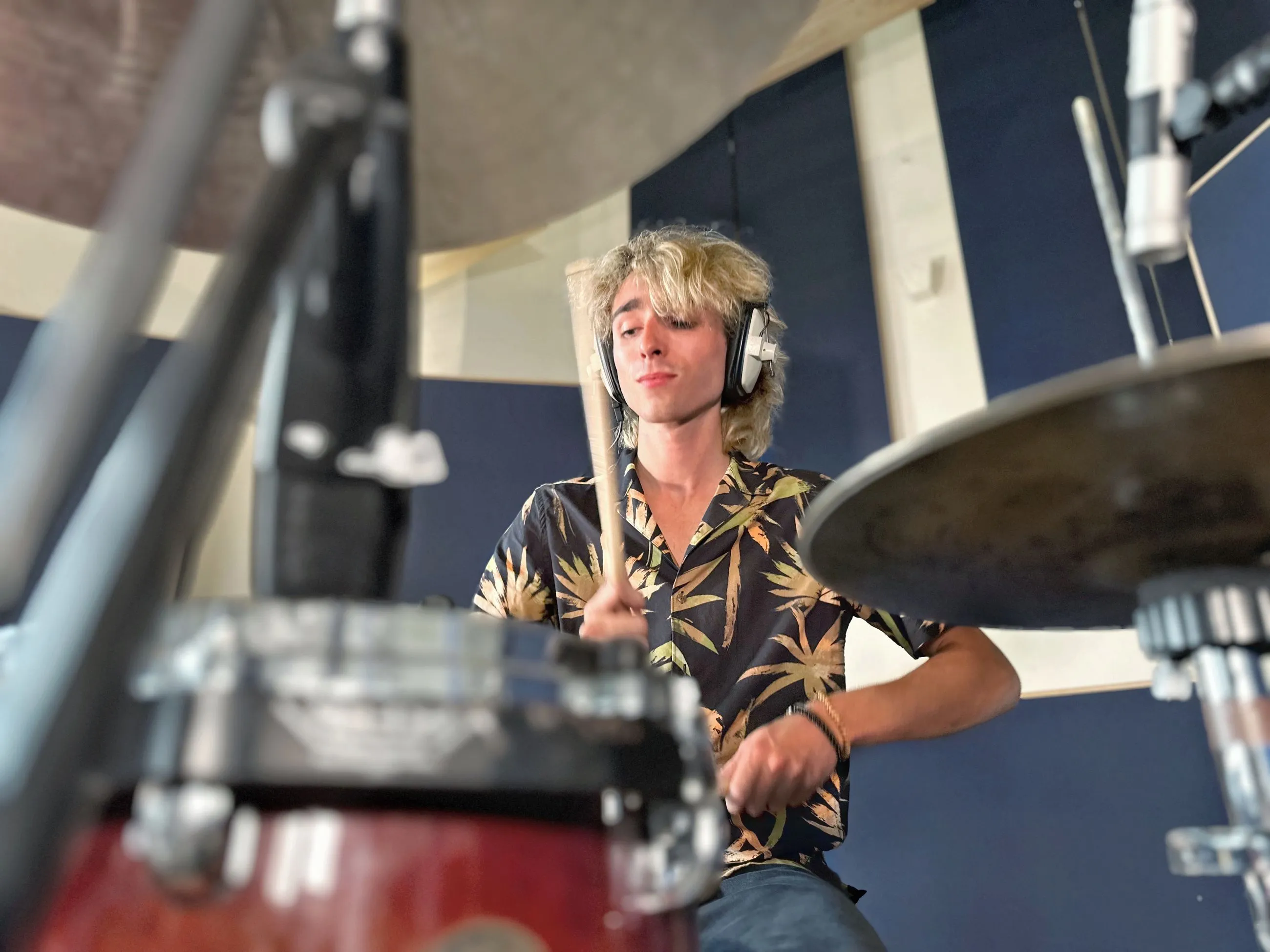Sam Harding playing a drum kit while wearing headphones