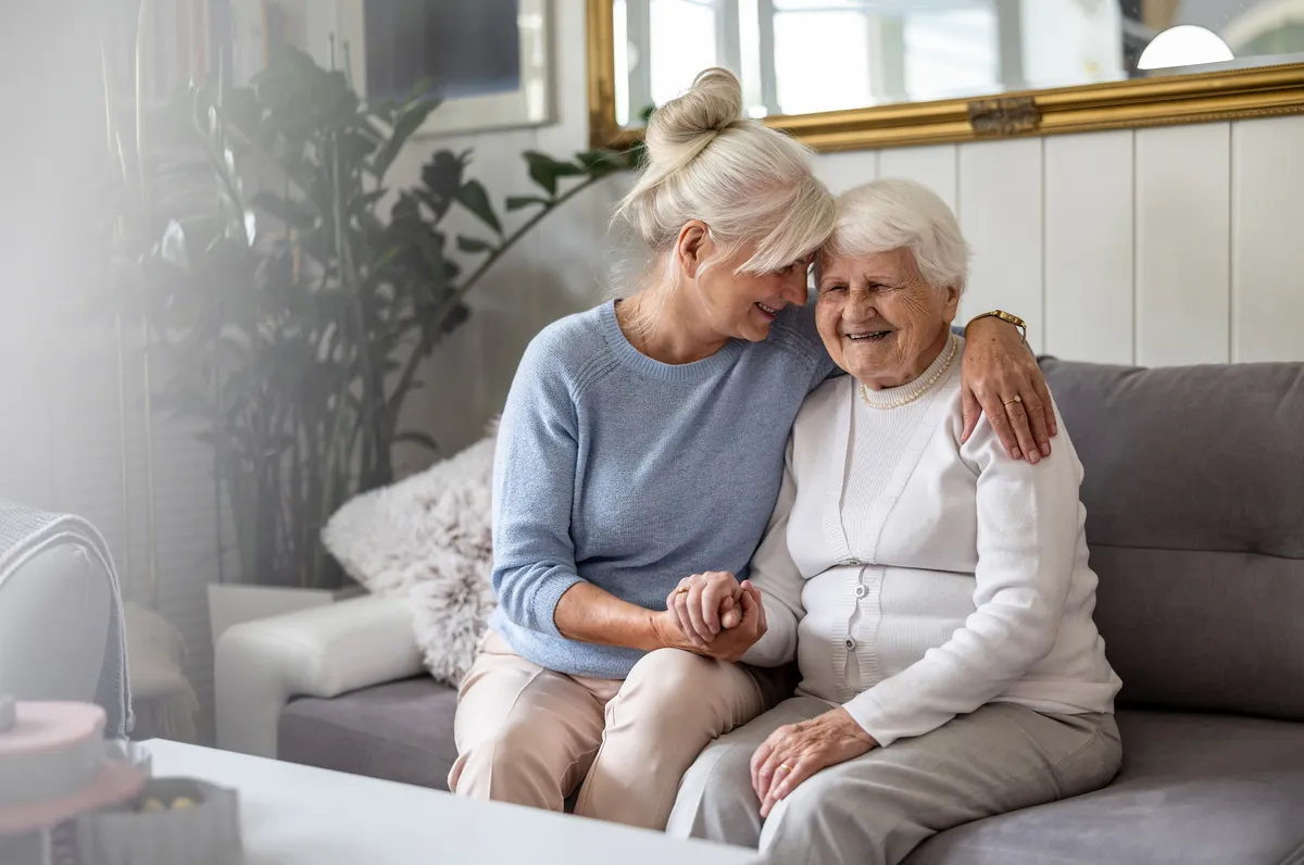 Adult daughter and mother sitting on a sofa.