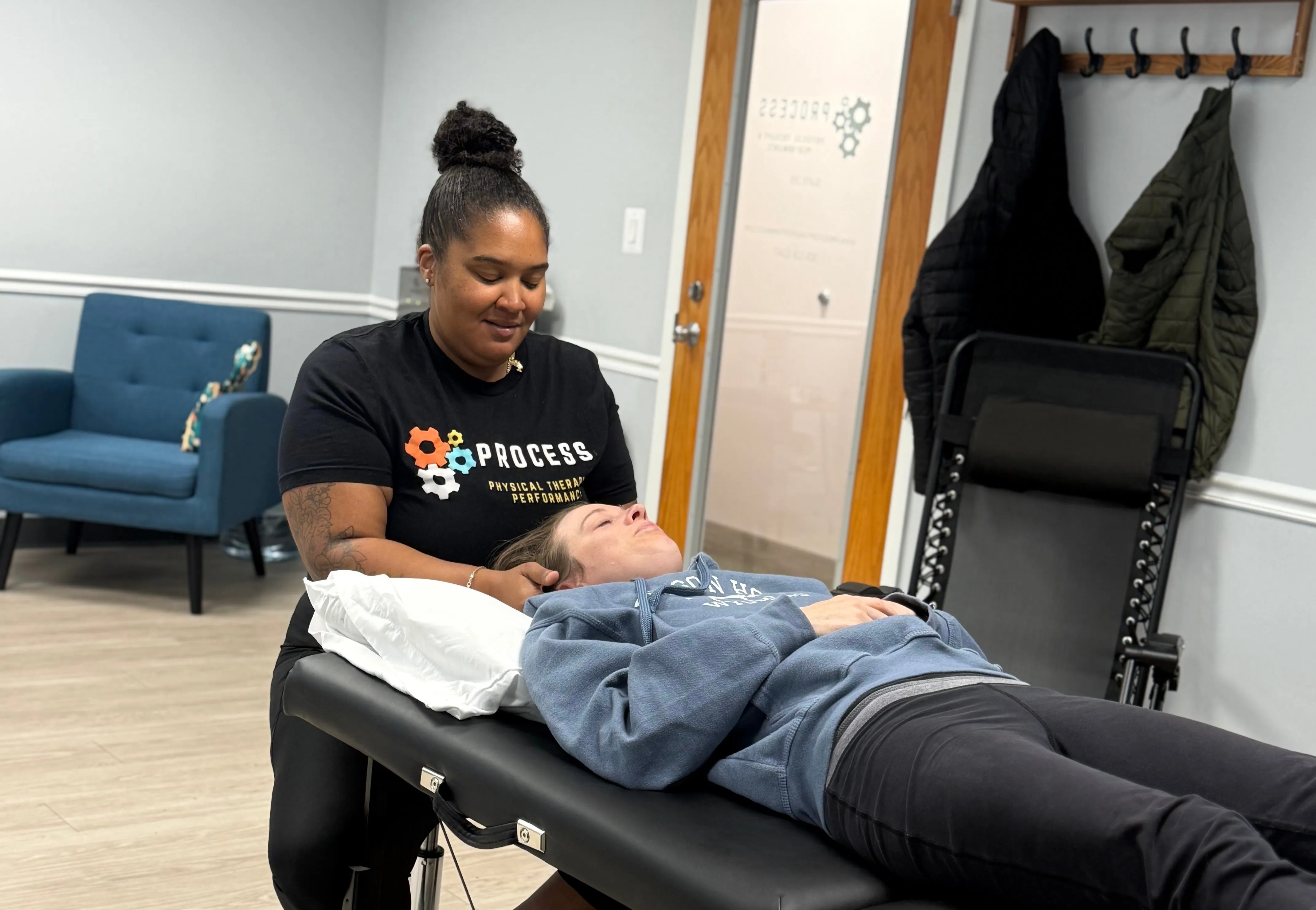 Physical therapist performing neck therapy on a woman lying on a treatment table in a clinic room.