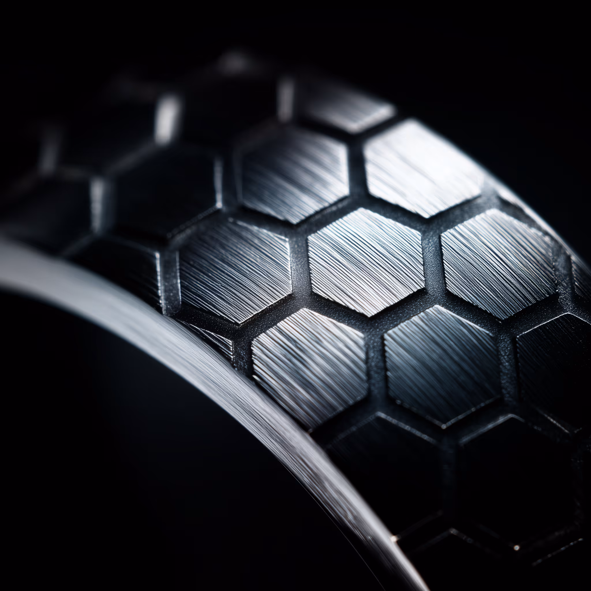 Close-up of a brushed metal surface with a pattern of hexagonal shapes on a curved object.