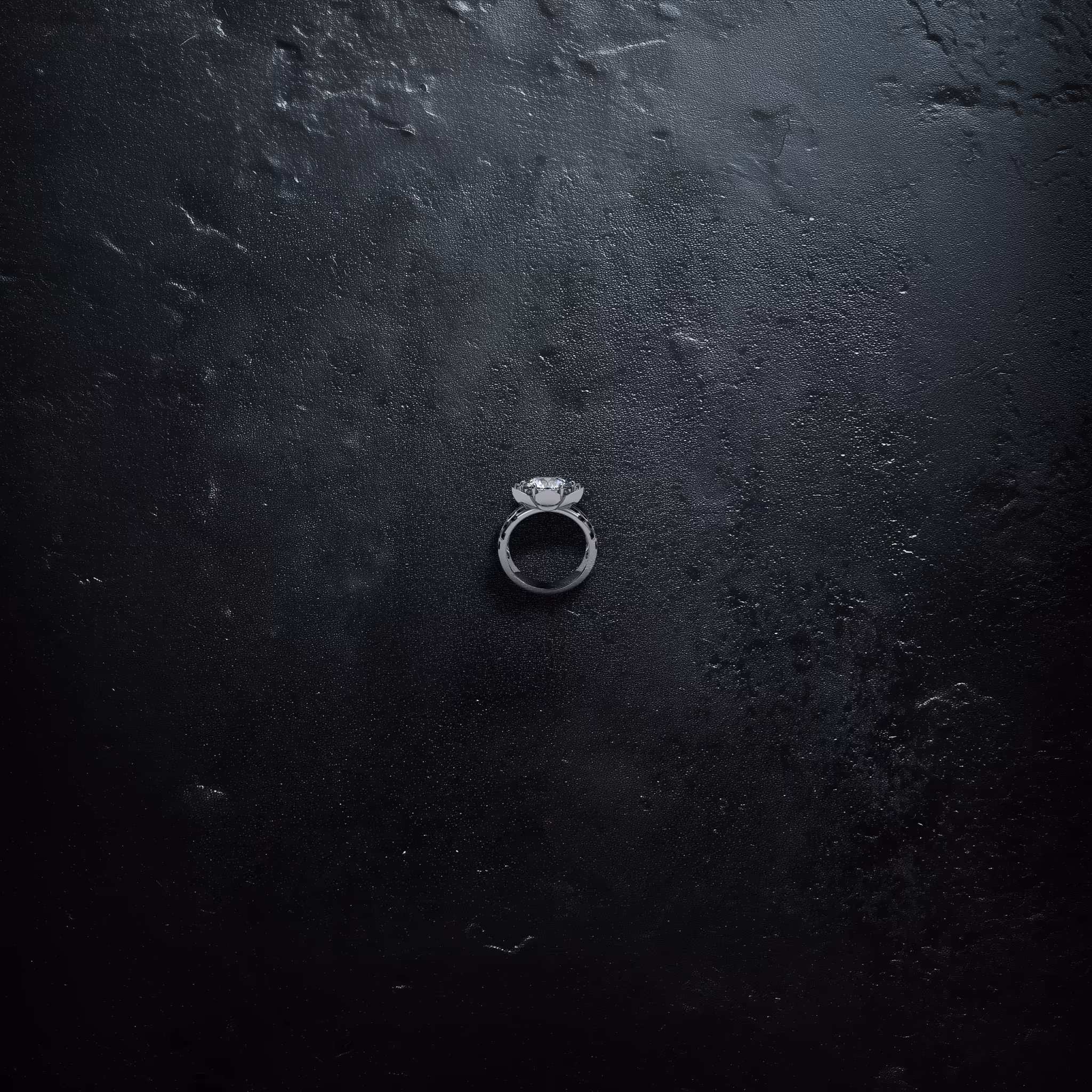 Silver ring with a large clear diamond on a textured black surface.
