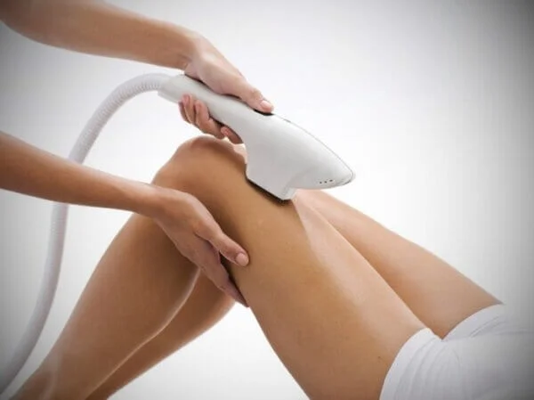 A woman using a hair dryer on her legs.