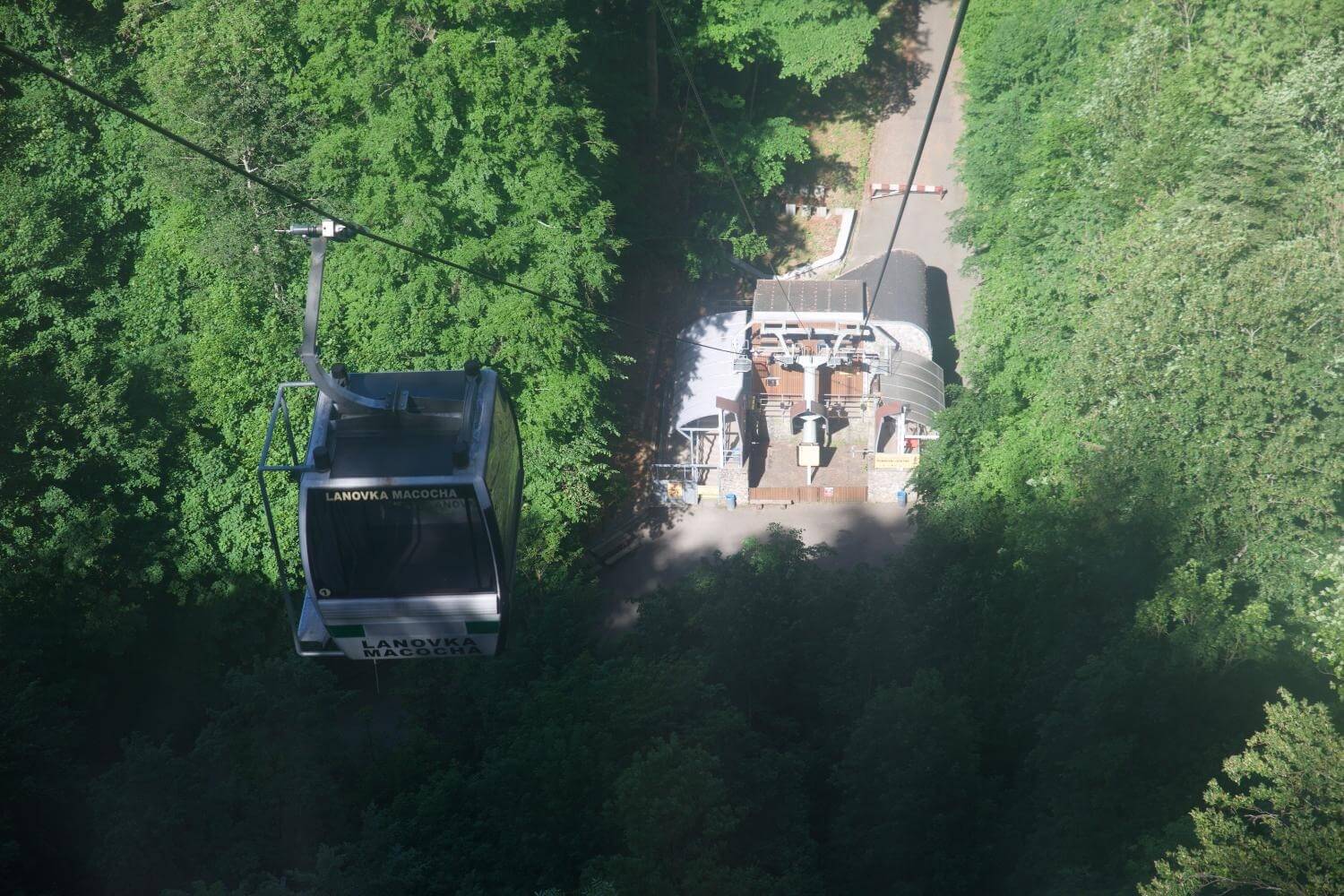 Lanovka Macocha cable car above forest trees approaching the cable car station.