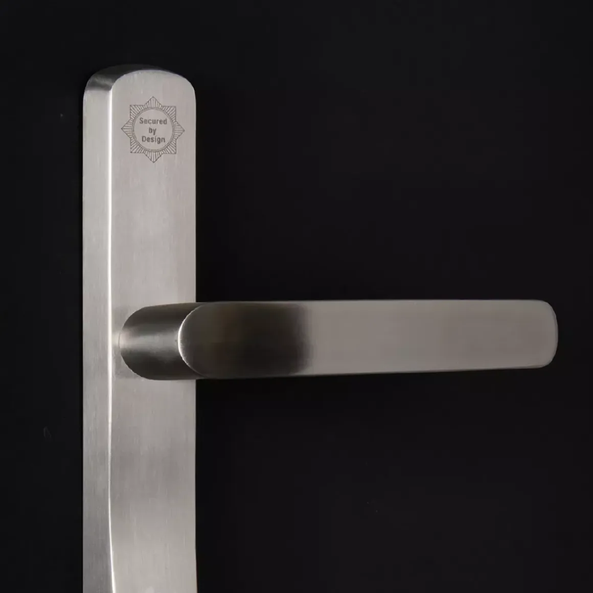 Brushed metal door handle with a badge stating 'Secured by Design' on a black background.