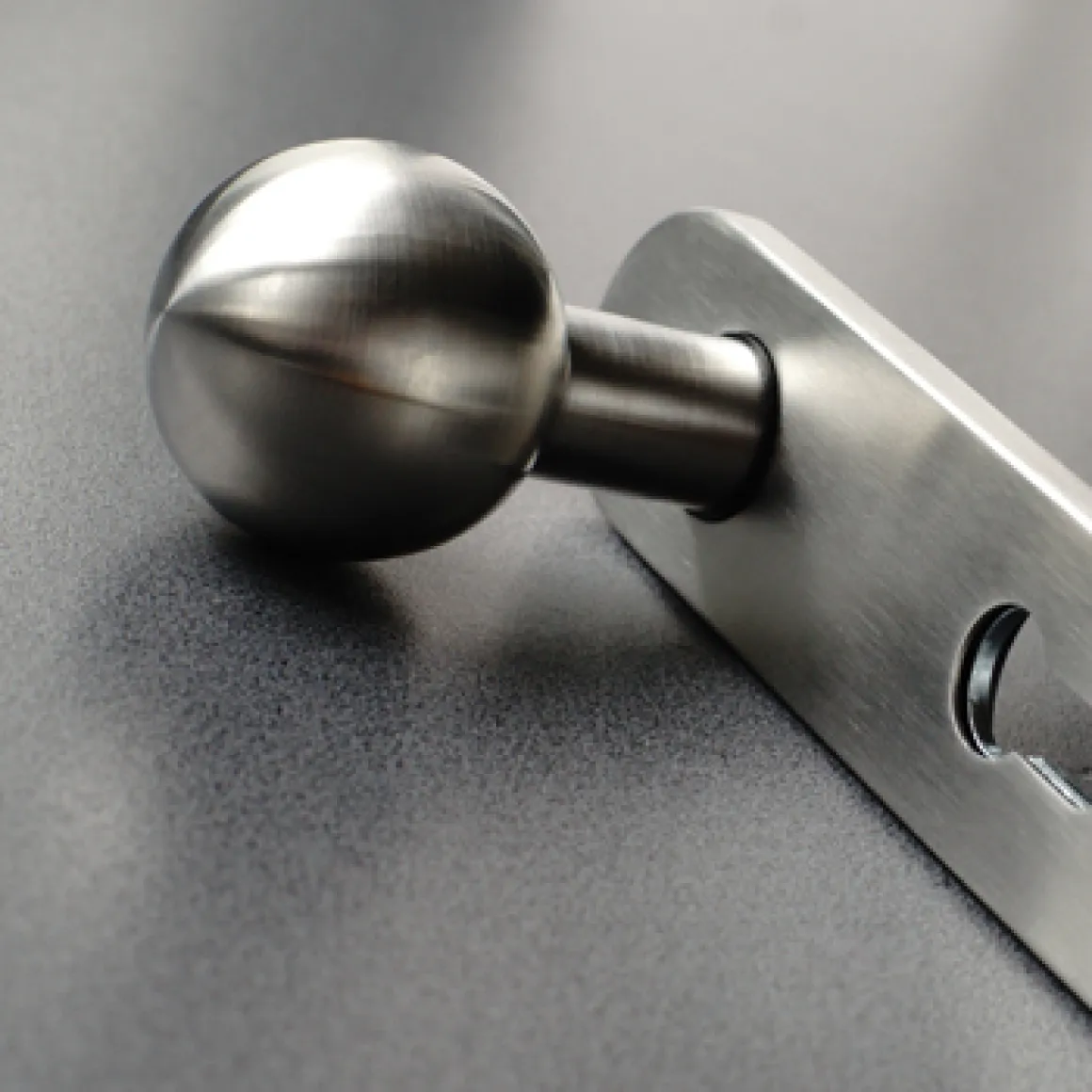 Close-up of a sleek, metallic round door handle attached to a gray door with a rectangular mounting plate.