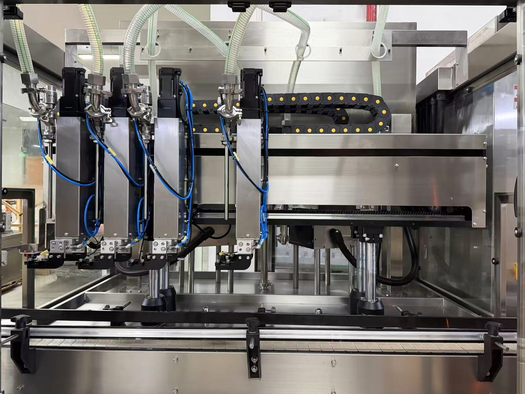 Industrial stainless steel machine with multiple nozzles and tubing for automated filling or processing.