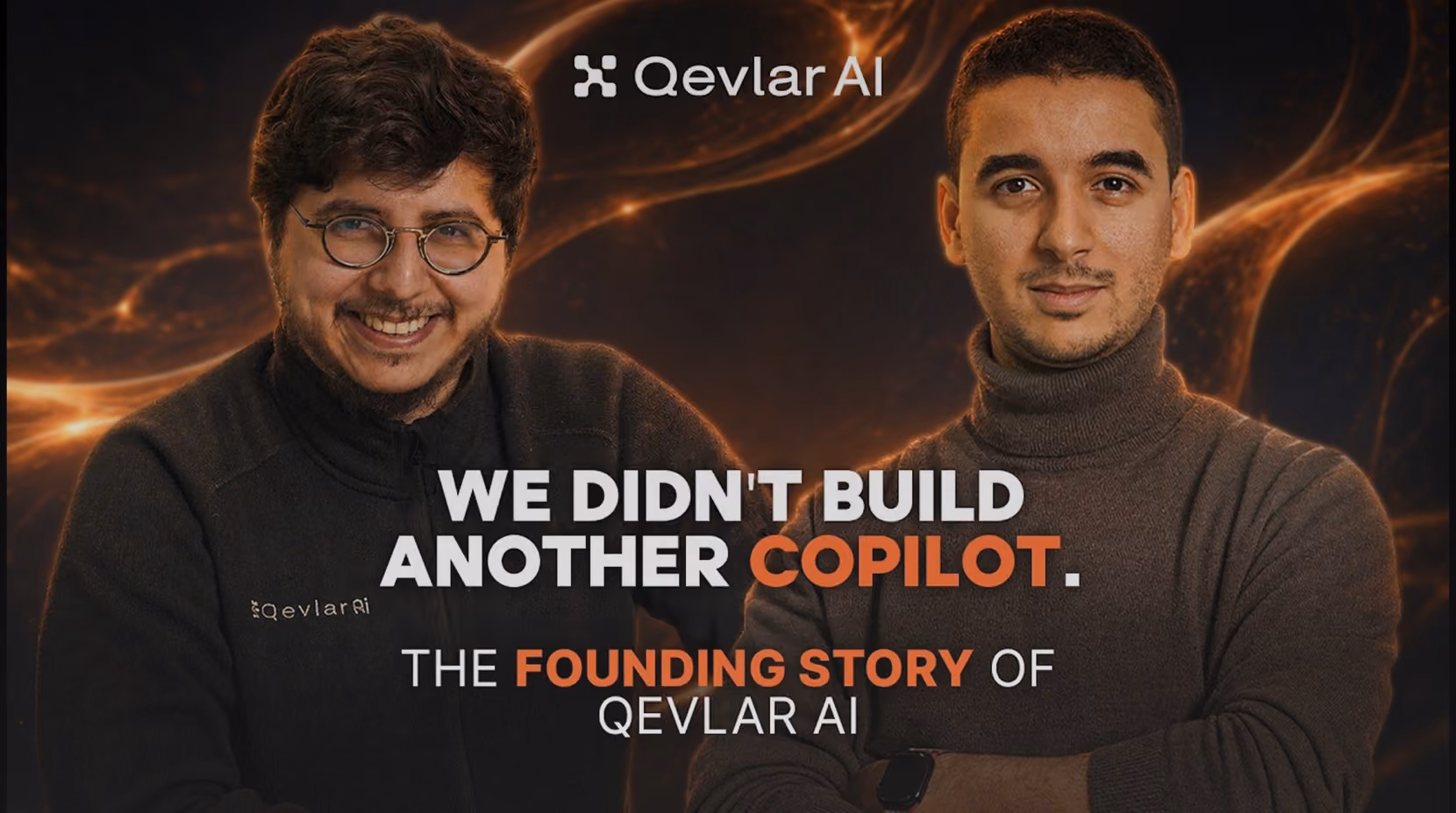Two men standing side by side in front of a dark background with orange light streaks, with text that reads: 'We didn't build another copilot. The founding story of Qevlar AI.' The smaller man on the left wears glasses and a black zip-up jacket, the man on the right wears a brown turtleneck sweater.
