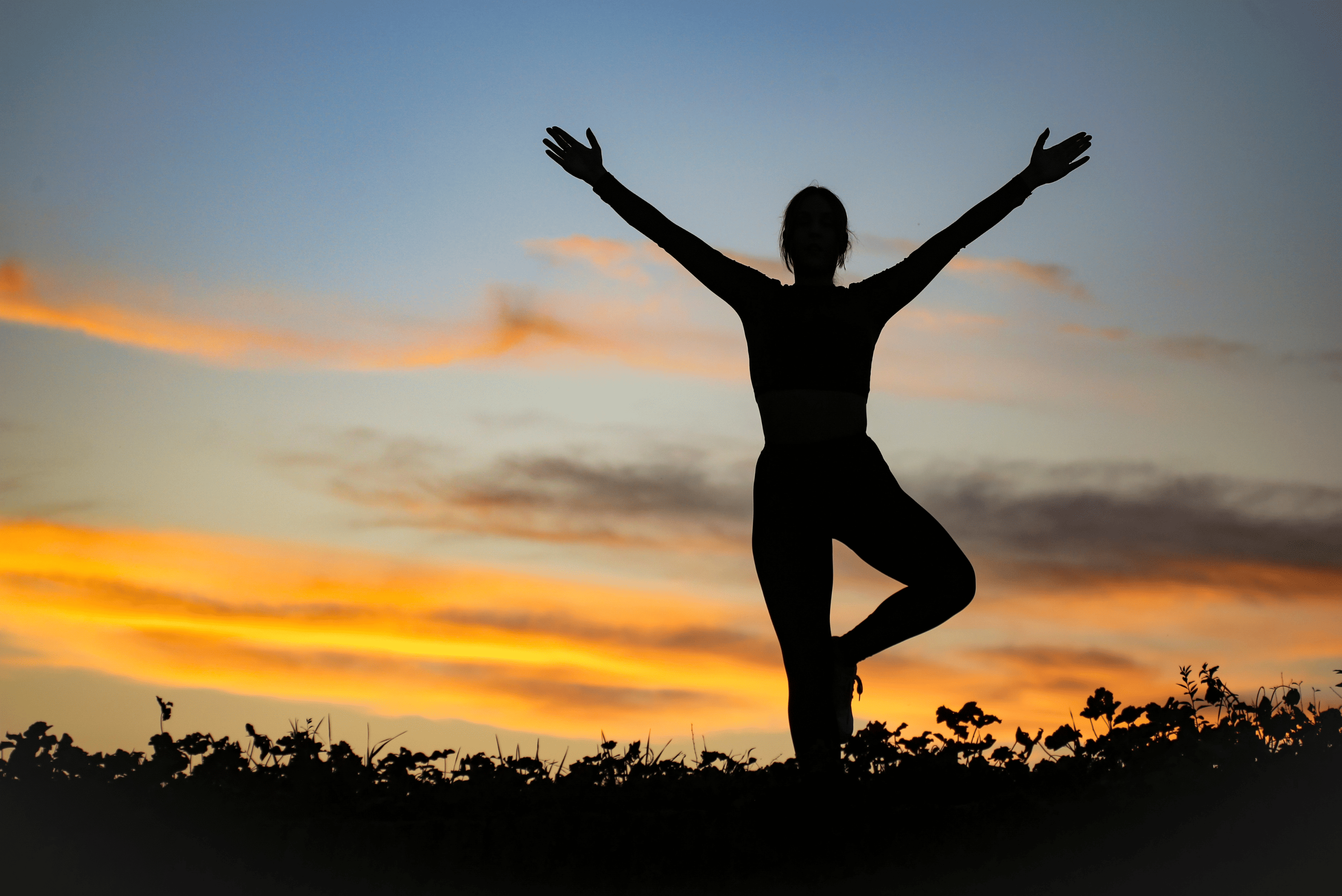 Silhouette d’une personne en posture de yoga au coucher du soleil, symbolisant bien-être, équilibre et sérénité.