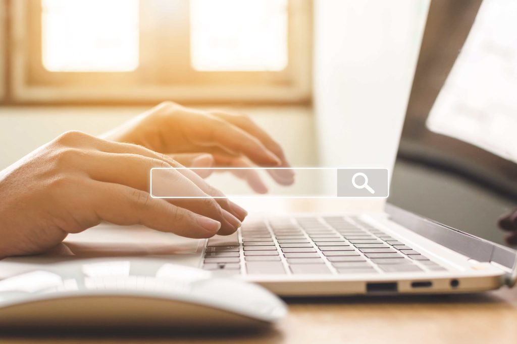 a person typing on a computer with a search bar icon over the image