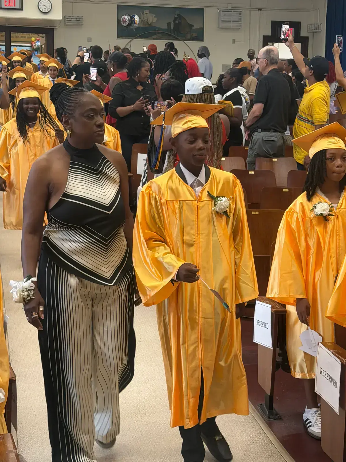 Students in gold cap and gown processing during graduation ceremony