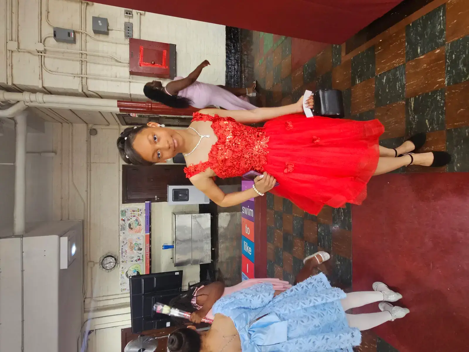 Student in red formal dress posing at school prom event