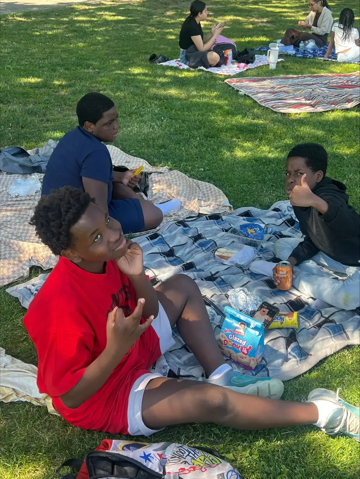 Students relaxing on blankets outdoors during a school picnic trip