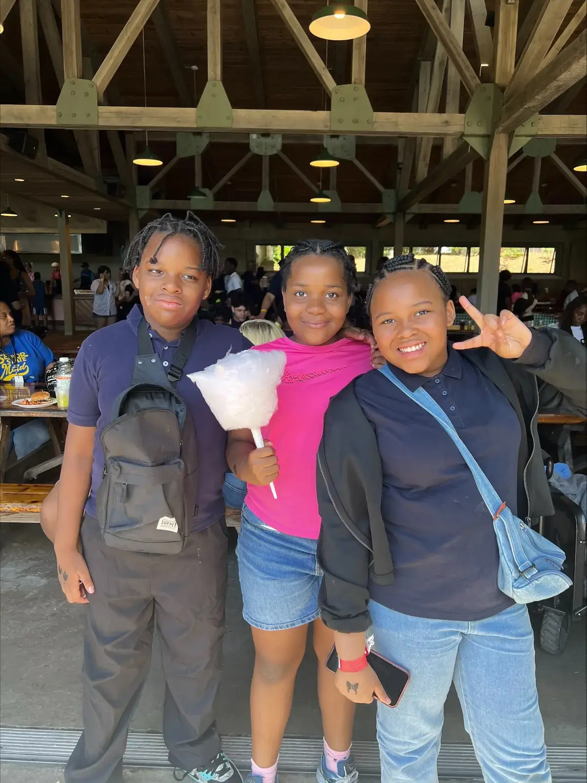 Three students smiling at a school trip holding cotton candy