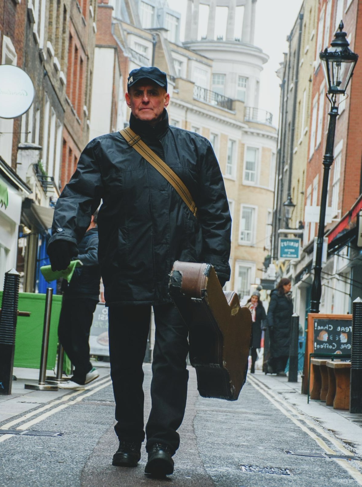 John Wroath walking with guitar case.