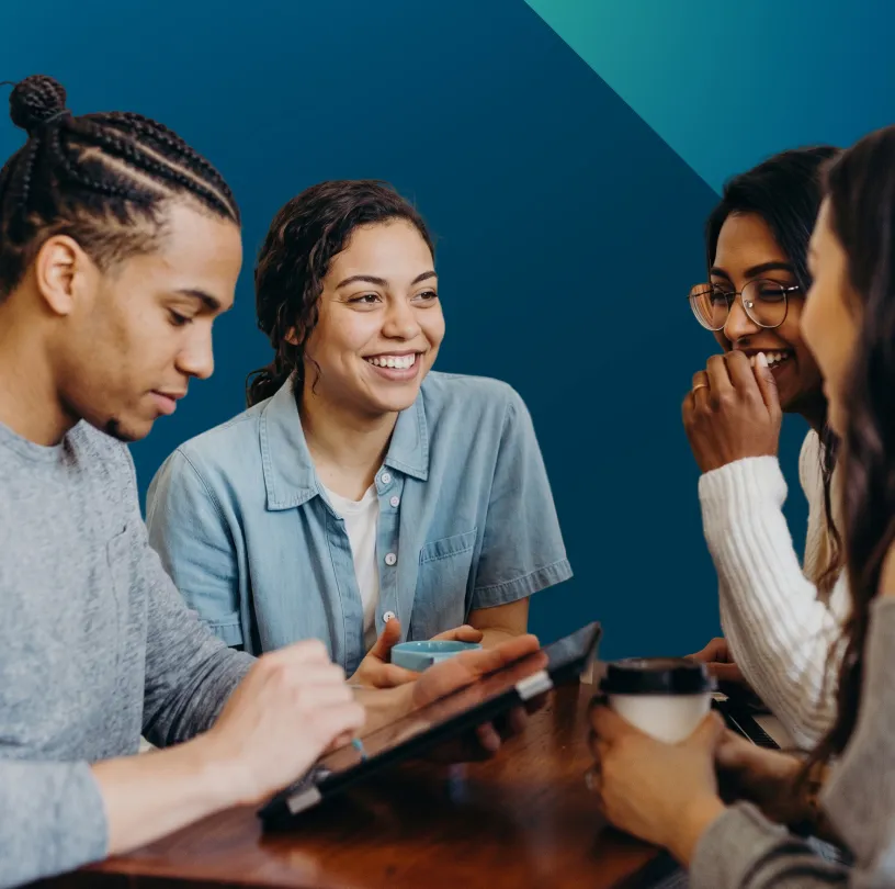 Quatre jeunes participants échangent en souriant autour d’une table avec une tablette