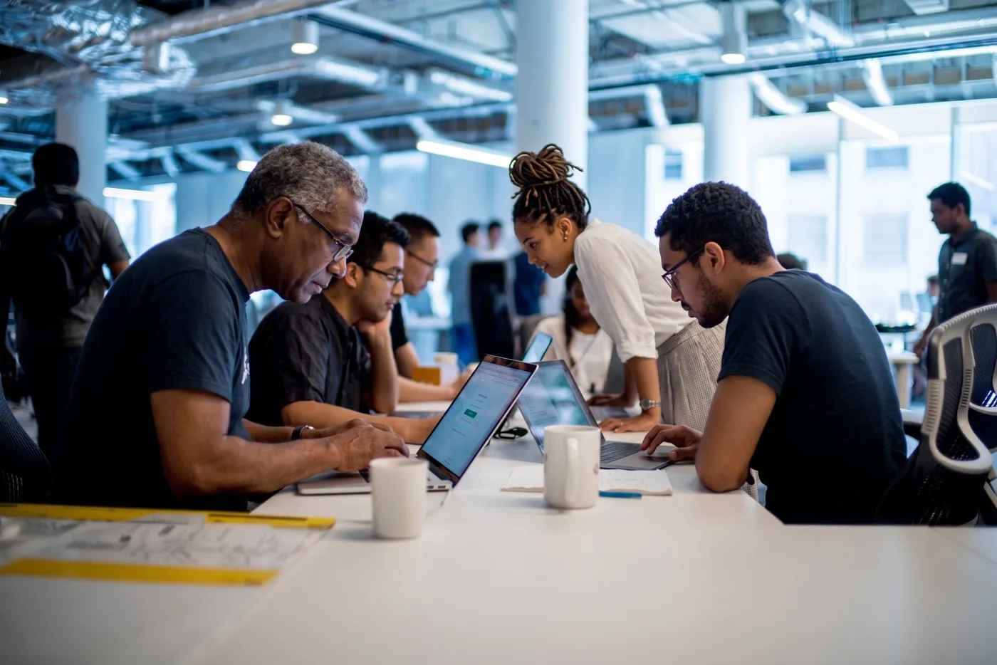 Participants concentrés sur leurs ordinateurs portables autour d’une grande table de travail