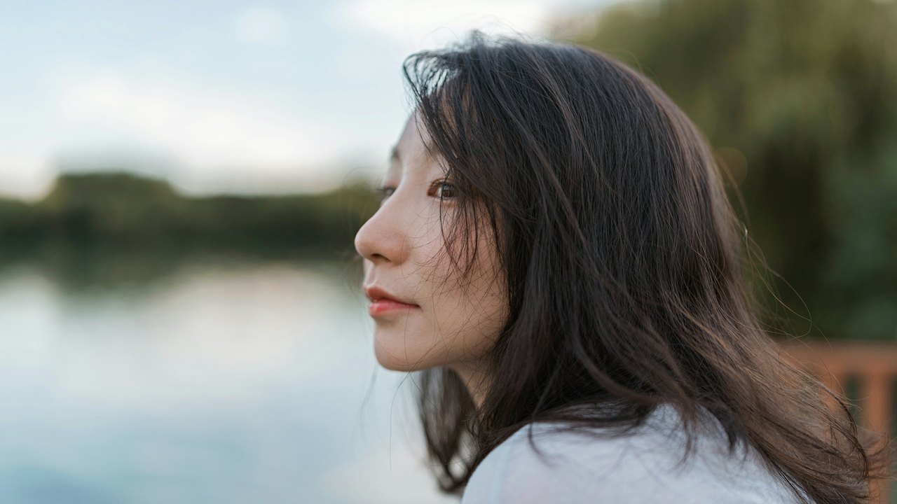 Woman in profile by a lake in soft daylight
