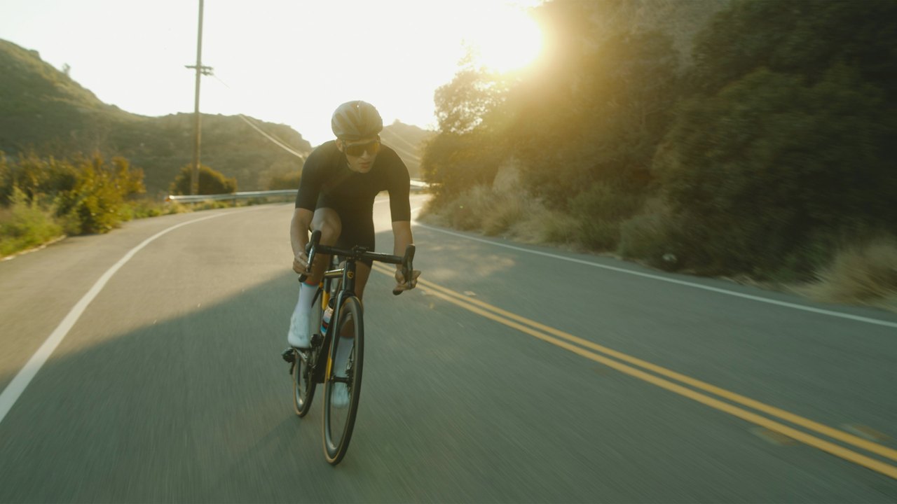 Cyclist riding along a sunlit road in the early morning