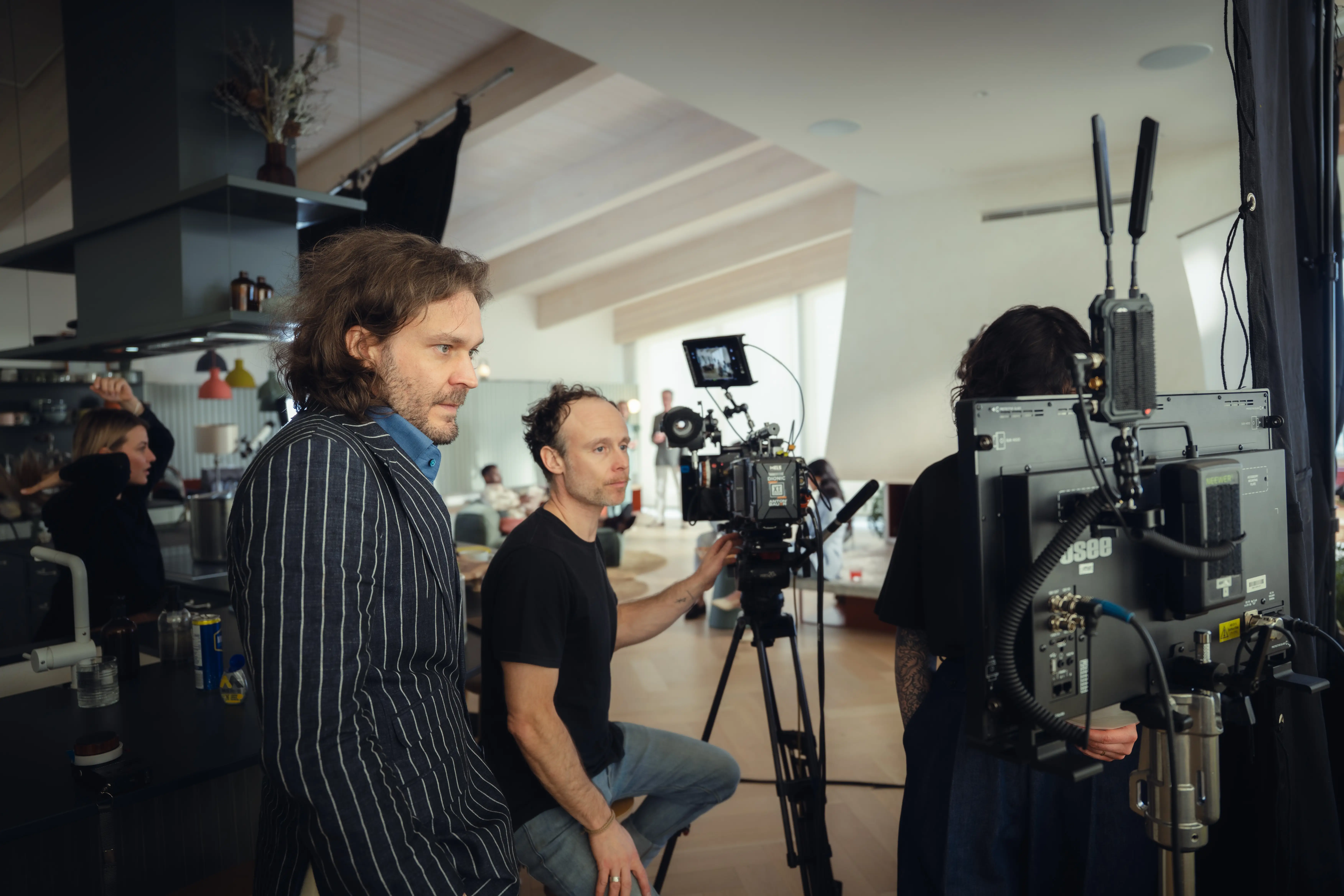 Équipe de tournage avec une caméra professionnelle et un moniteur dans un intérieur moderne.