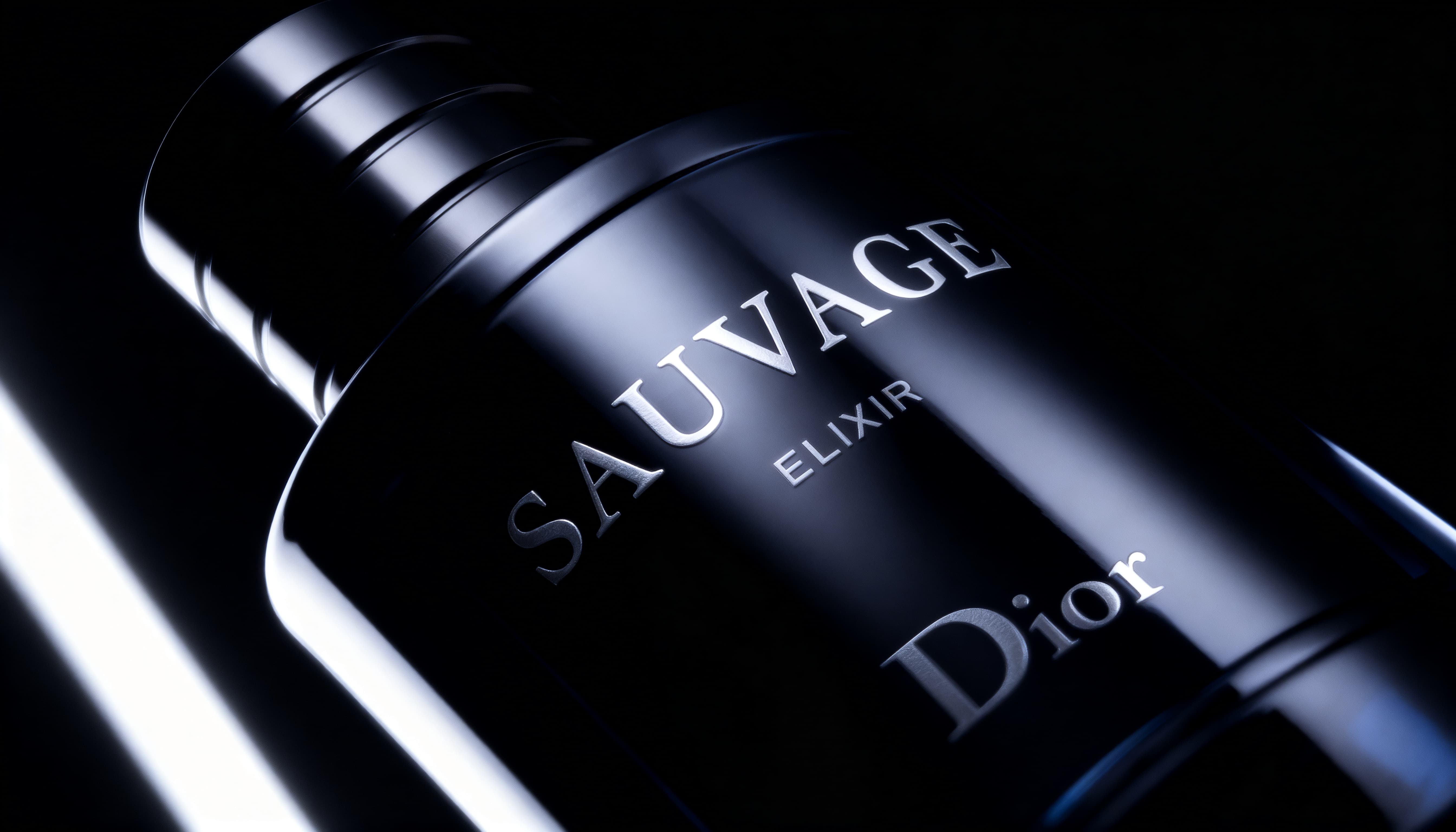 Close-up of a black bottle of Sauvage Elixir by Dior with dramatic lighting on a dark background.