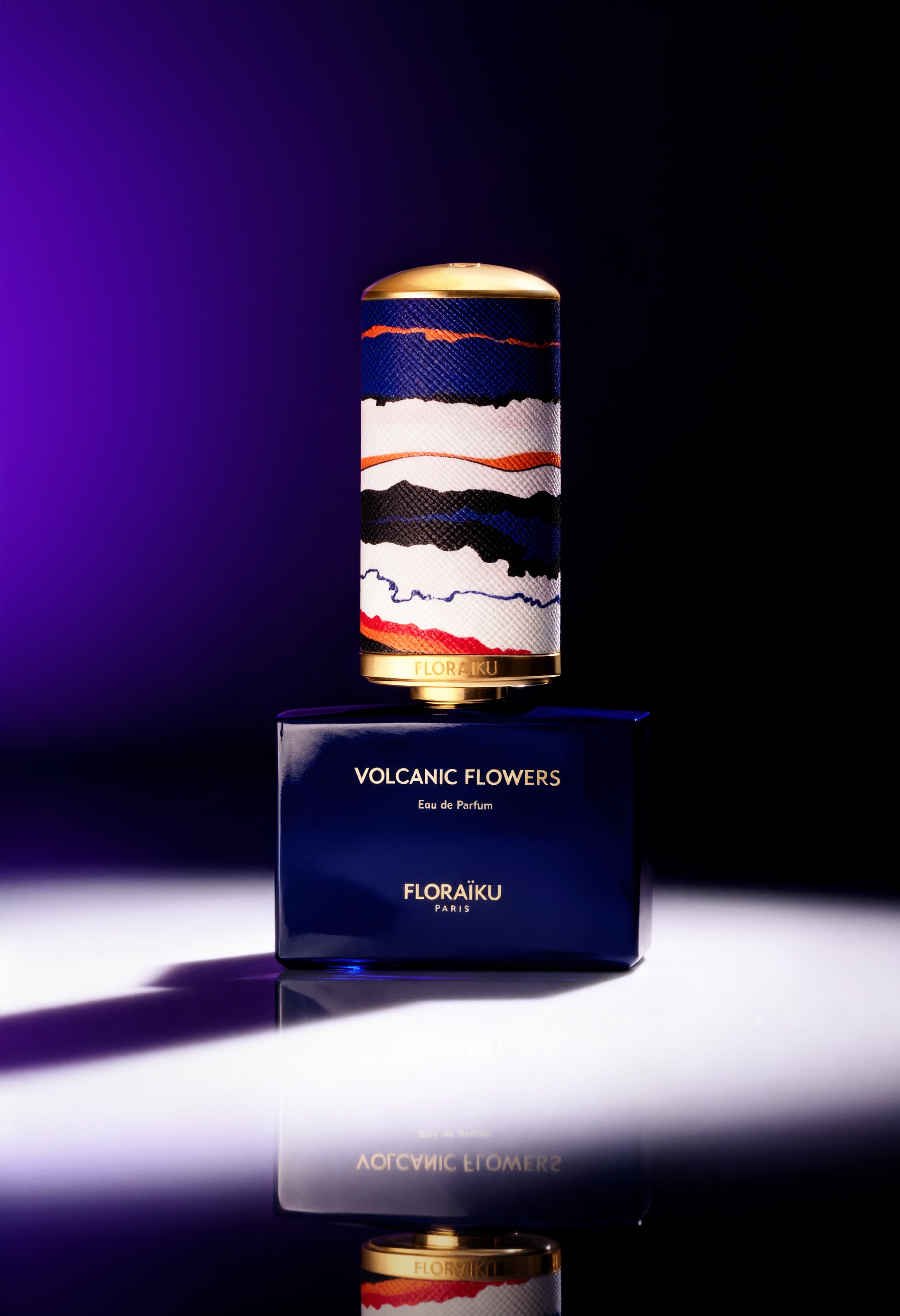 Blue Volcanic Flowers perfume bottle by Floraïku with colorful textured cap on reflective surface.